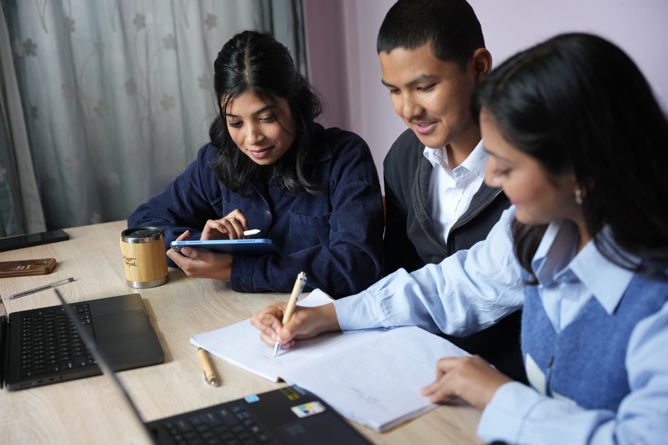 Digit Nepal team members reviewing notes and a tablet together